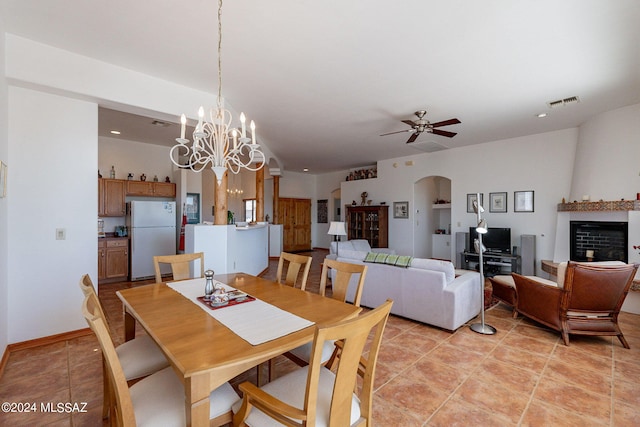 tiled dining room with ceiling fan with notable chandelier