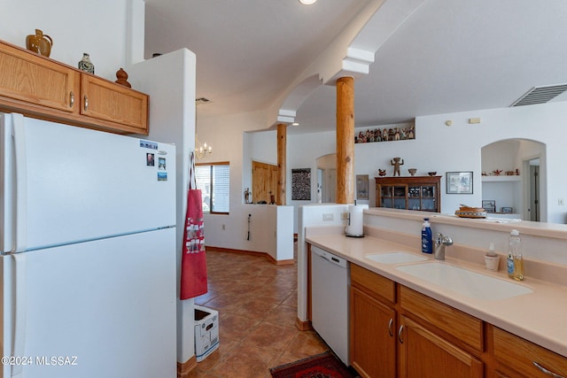 kitchen with tile flooring, decorative columns, an inviting chandelier, white appliances, and sink