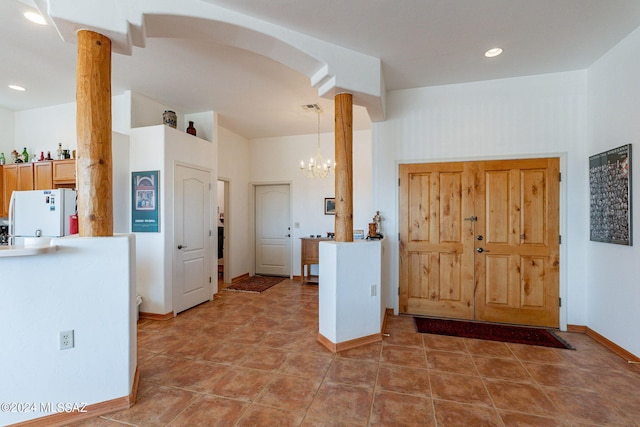 kitchen featuring decorative columns, tile flooring, white refrigerator, and a chandelier