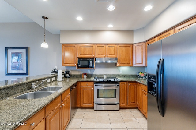 kitchen featuring hanging light fixtures, stainless steel appliances, light tile flooring, dark stone counters, and sink