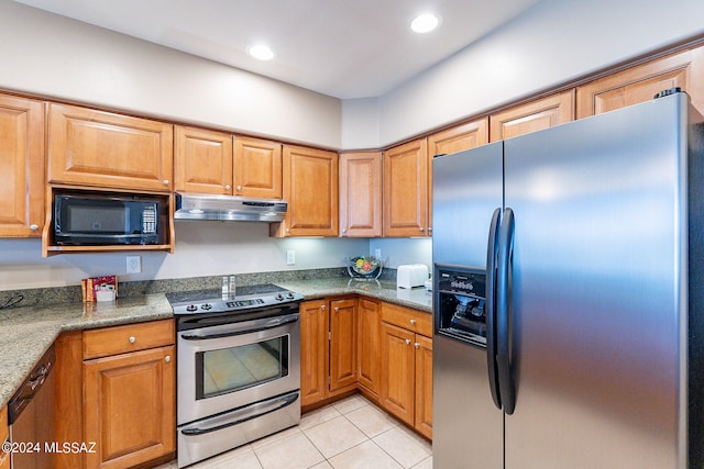 kitchen featuring dark stone countertops, stainless steel appliances, and light tile floors