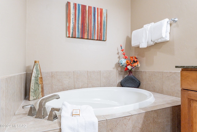 bathroom featuring tiled tub and vanity