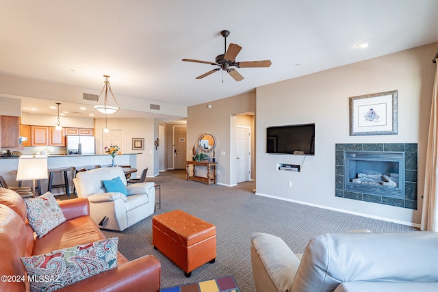 living room featuring ceiling fan, carpet floors, and a fireplace