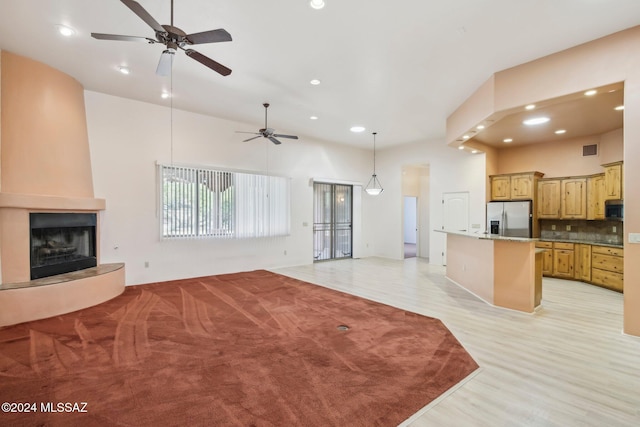 kitchen with appliances with stainless steel finishes, a large fireplace, backsplash, hanging light fixtures, and a center island