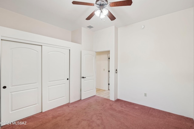 unfurnished bedroom featuring light carpet, a closet, and ceiling fan