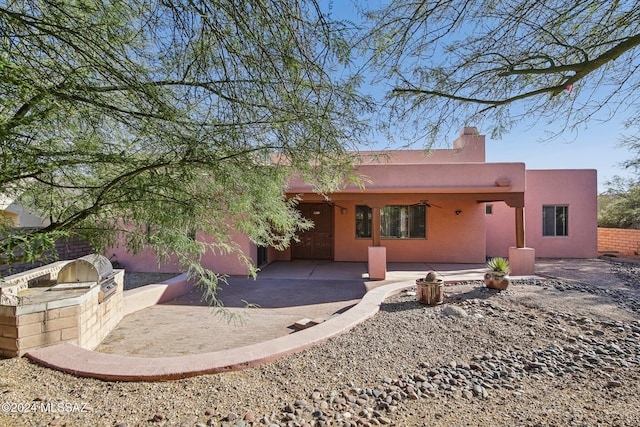 rear view of property with exterior kitchen, a patio, and ceiling fan