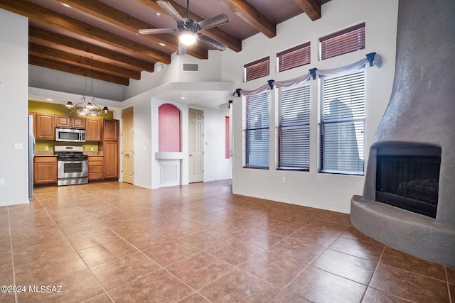 unfurnished living room featuring ceiling fan, beam ceiling, a large fireplace, and light tile flooring