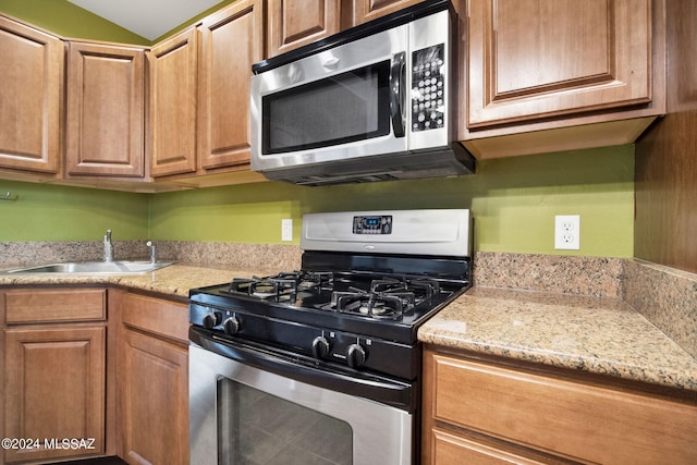 kitchen featuring sink, light stone counters, and appliances with stainless steel finishes