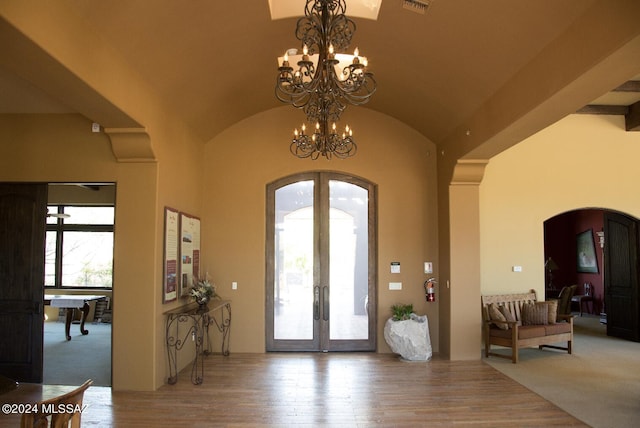 entryway with wood-type flooring, a chandelier, french doors, and vaulted ceiling