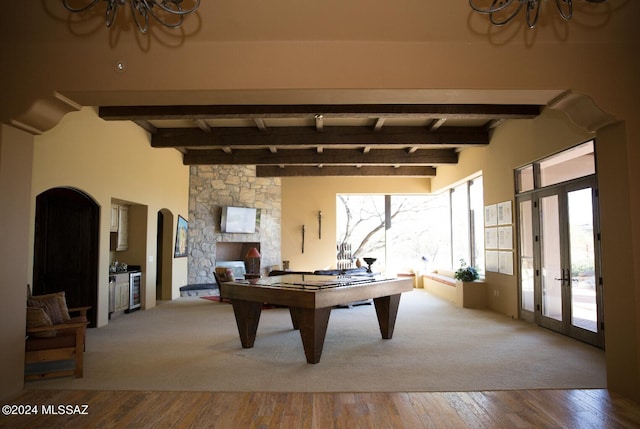 rec room featuring beamed ceiling, a notable chandelier, hardwood / wood-style flooring, and french doors