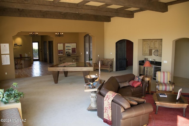 living room with a notable chandelier, beverage cooler, beamed ceiling, and carpet flooring