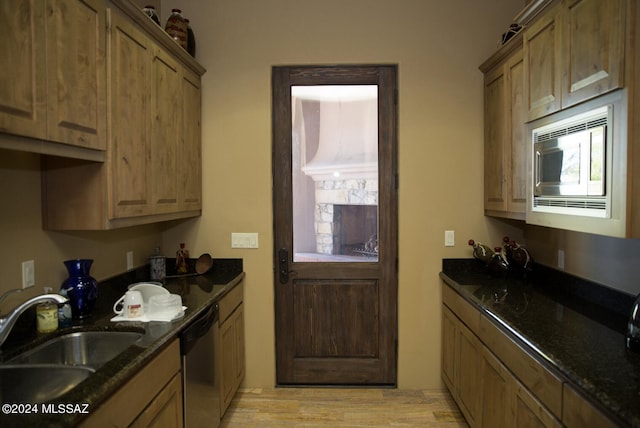 kitchen featuring dark stone countertops, appliances with stainless steel finishes, sink, and light wood-type flooring