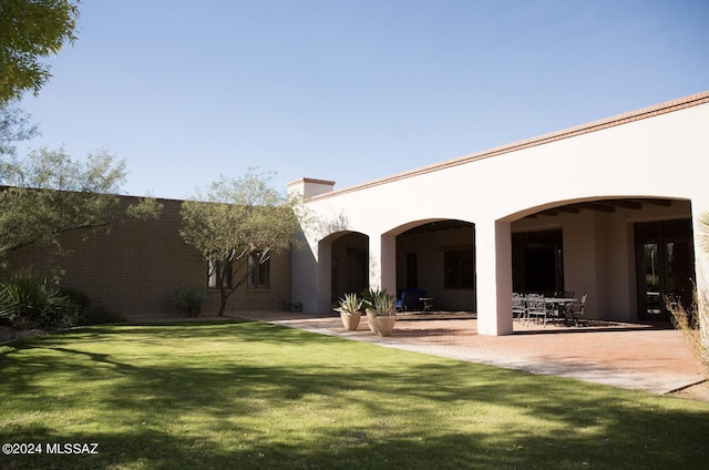 rear view of house with a patio and a lawn