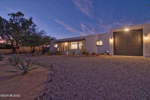 pueblo-style home featuring an attached garage, fence, and stucco siding