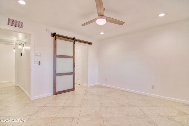 tiled empty room with a barn door and ceiling fan