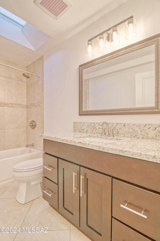 full bathroom with a skylight, vanity, tiled shower / bath combo, tile patterned flooring, and toilet