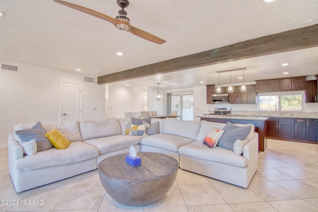 living room with beam ceiling, light tile patterned floors, ceiling fan, and sink