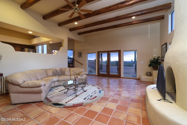 tiled living room with beamed ceiling, a towering ceiling, ceiling fan, and french doors