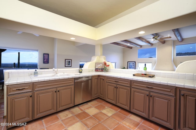 kitchen featuring sink, tile countertops, stainless steel dishwasher, and kitchen peninsula