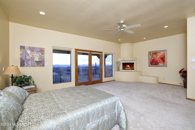 bedroom with carpet, a large fireplace, access to outside, and ceiling fan