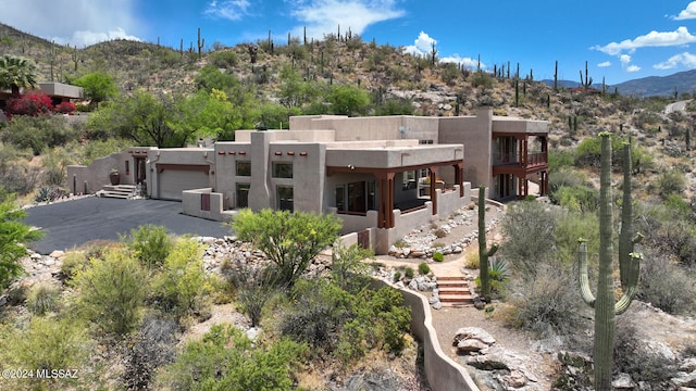 view of front of property featuring a mountain view, a garage, driveway, stairway, and stucco siding