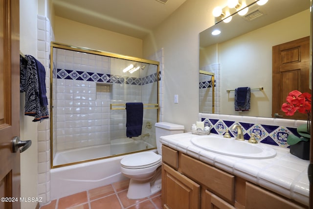 full bathroom with vanity, bath / shower combo with glass door, tile patterned floors, and toilet