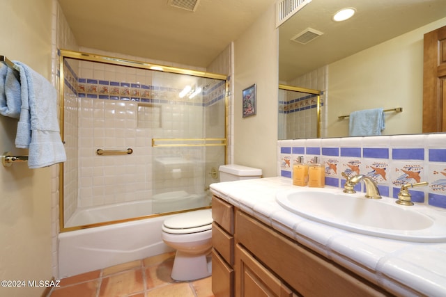 full bathroom featuring tile patterned flooring, vanity, shower / bath combination with glass door, and toilet