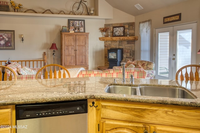 kitchen with light stone counters, vaulted ceiling, and stainless steel dishwasher