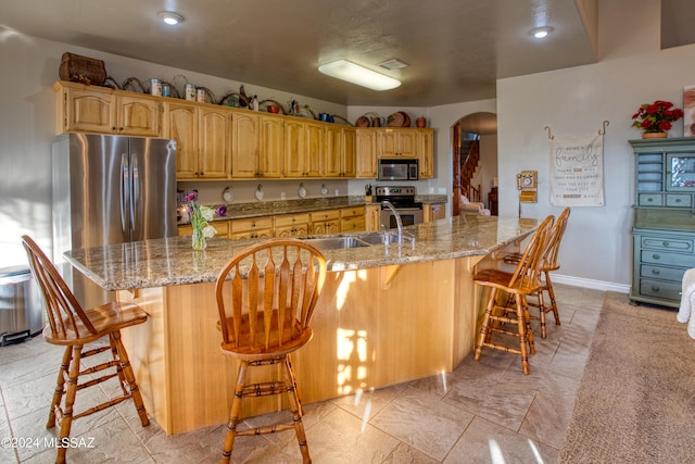 kitchen with light tile flooring, stainless steel appliances, a kitchen breakfast bar, and a large island with sink