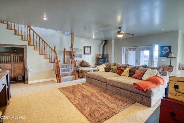 living room featuring french doors, a wood stove, light carpet, and ceiling fan