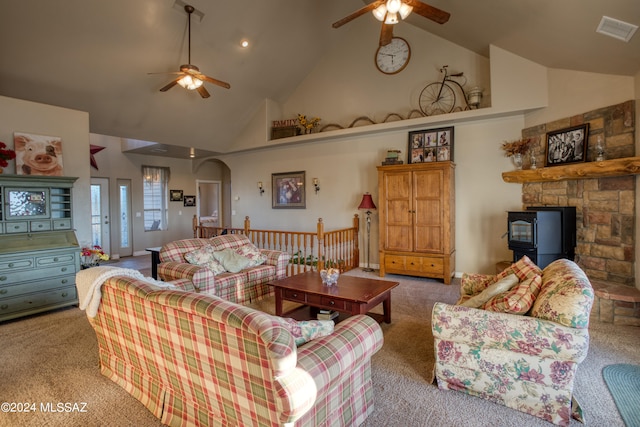 living room with a fireplace, a wood stove, ceiling fan, and carpet flooring