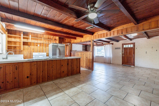 kitchen with beamed ceiling, wooden ceiling, light tile flooring, and stainless steel refrigerator