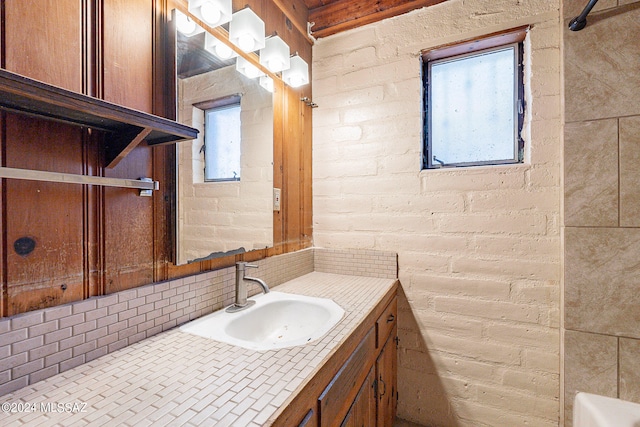 bathroom featuring brick wall and vanity