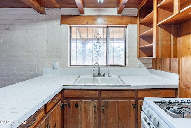 kitchen featuring brick wall, sink, and beam ceiling