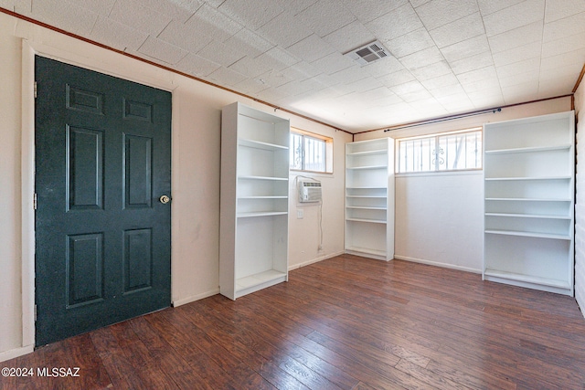 interior space with dark hardwood / wood-style floors and a wall unit AC