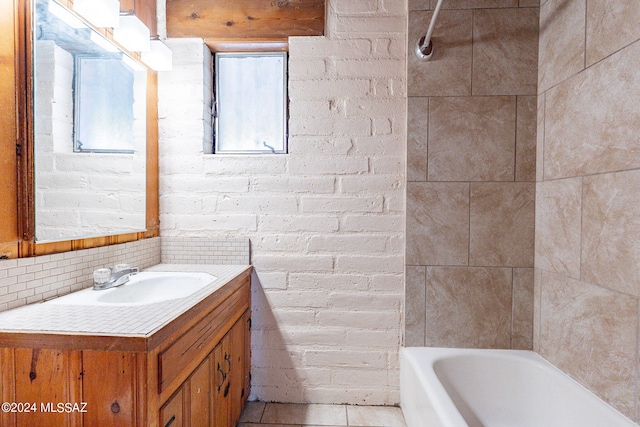 bathroom with tiled shower / bath combo, brick wall, and large vanity