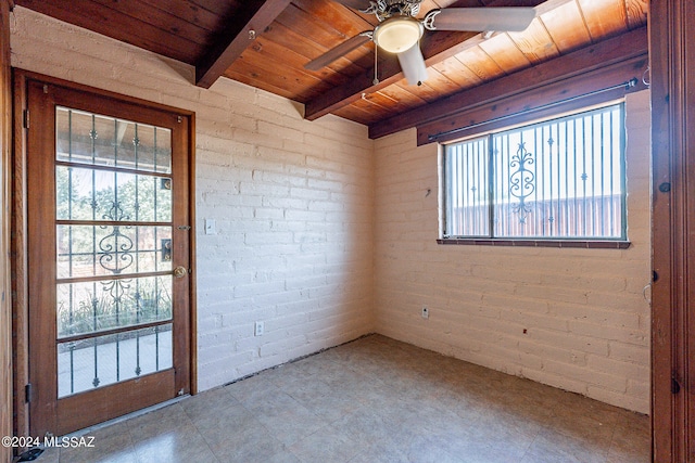 empty room featuring tile flooring, brick wall, wood ceiling, and ceiling fan