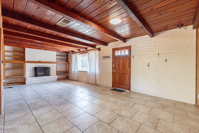 unfurnished living room with a fireplace, brick wall, beamed ceiling, wood ceiling, and light tile floors