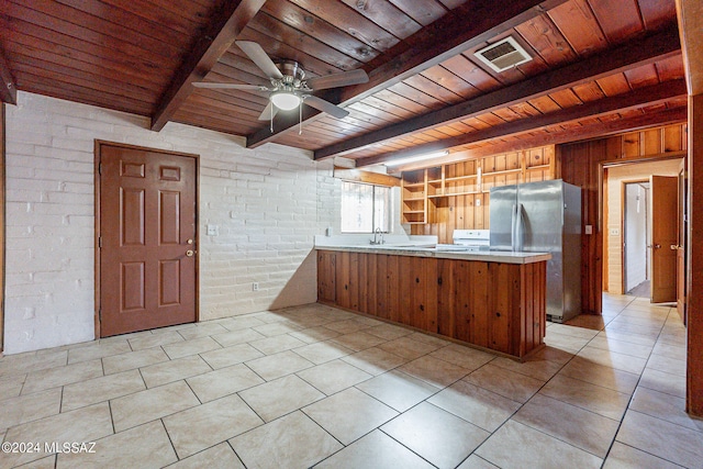 kitchen with brick wall, stainless steel fridge, beamed ceiling, wood ceiling, and light tile flooring