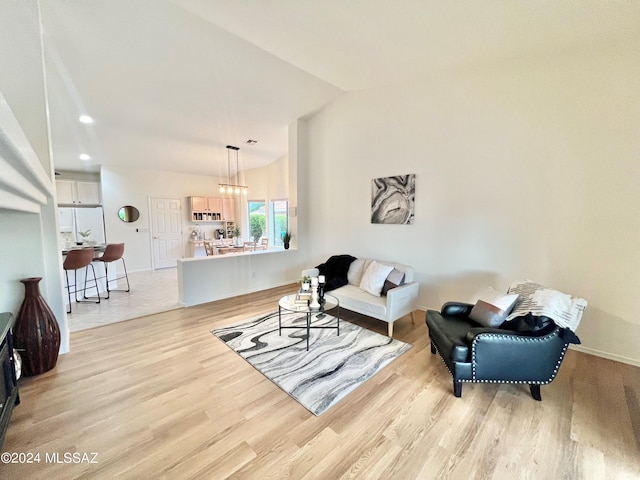 living area with lofted ceiling, recessed lighting, baseboards, and light wood finished floors