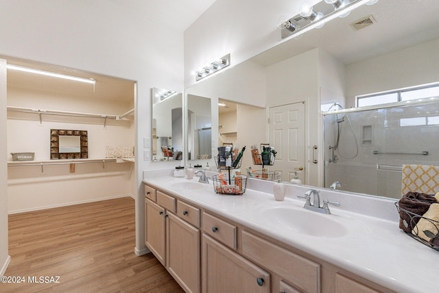 bathroom with wood-type flooring, a shower with door, and vanity