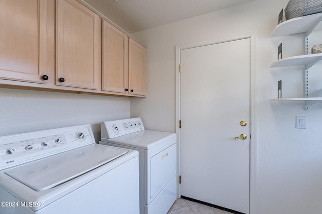 laundry area featuring light tile patterned floors, cabinet space, and washer and clothes dryer