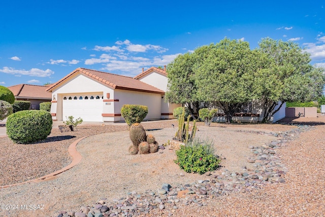 view of front of house featuring a tile roof, an attached garage, and stucco siding