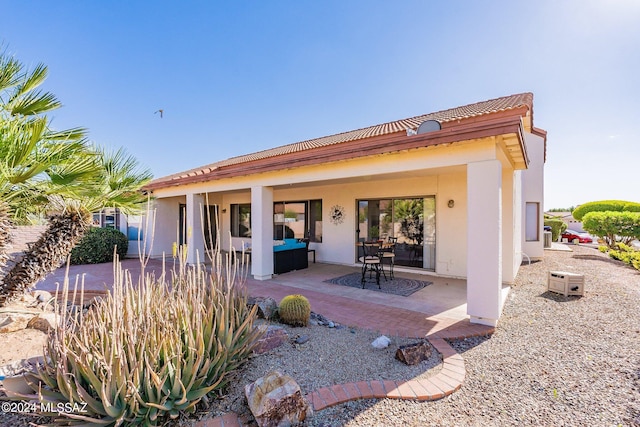 rear view of property featuring stucco siding, a patio, and a tile roof