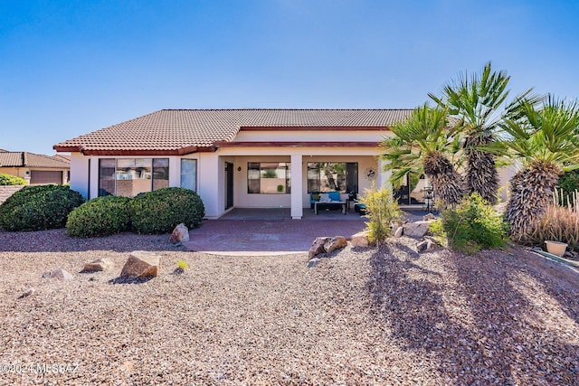 back of property with stucco siding, a patio, and a tiled roof