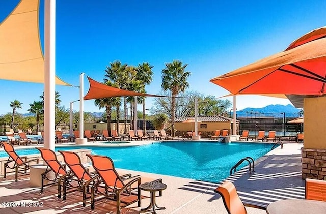 community pool featuring a mountain view, fence, and a patio area