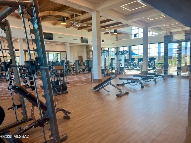 workout area featuring wood finished floors, coffered ceiling, and ceiling fan