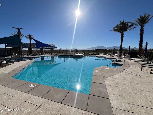 pool featuring fence, a patio area, and a mountain view