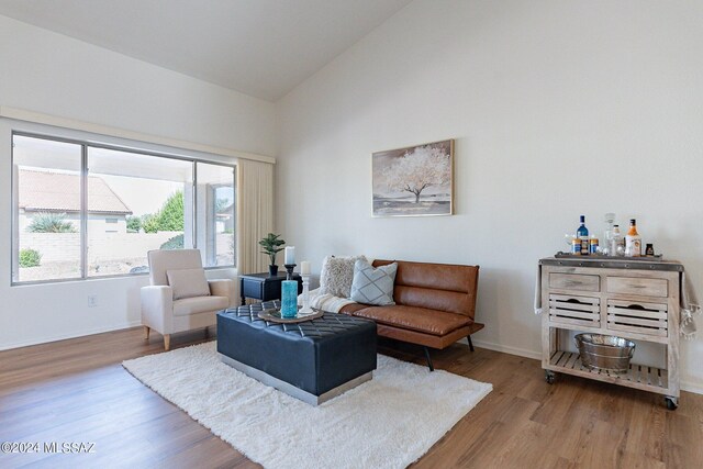 living area featuring lofted ceiling, light hardwood / wood-style flooring, and ceiling fan