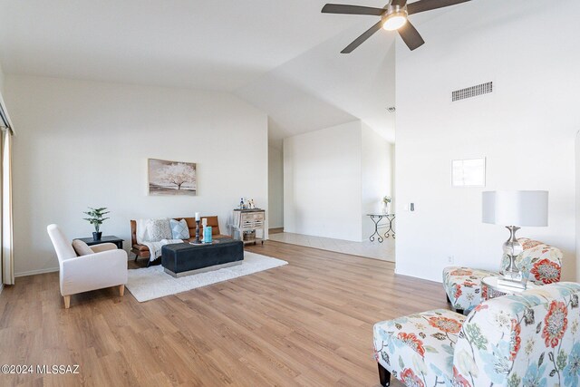 living area featuring a high ceiling, ceiling fan, and light wood-type flooring